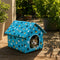 Niche pour chat extérieur hiver bleue avec motifs de chats et toit rembourré, posée sur une terrasse en bois au soleil