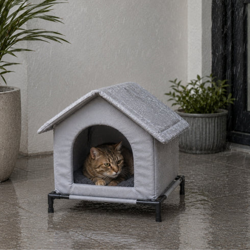 Abri pour chat extérieur gris imperméable avec toit protecteur et pieds surélevés, installé sous la pluie avec un chat à l’abri dedans