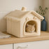 Cabane pour chat intérieur en peluche beige posée sur un plan de travail