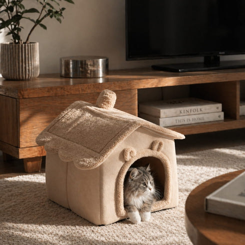 Cabane intérieure beige pour chat avec toit moelleux et entrée arrondie, installée dans un salon chaleureux avec un chat allongé à l’intérieur