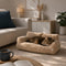 Chat allongé sur un canapé pour chat en tissu bouclette beige, couchage moelleux et confortable dans un salon chaleureux.