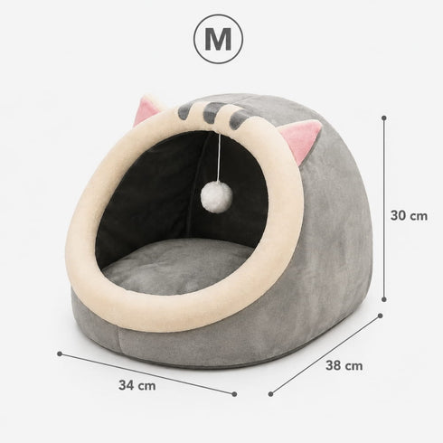 Cocon pour chat gris en peluche avec coussin intégré, oreilles décoratives et pompon suspendu, dimensions taille M indiquées sur l’image.