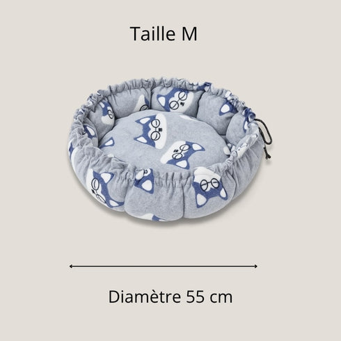 Couffin pour chat en polaire grise, taille M, avec motifs de têtes de chat bleues, présenté en vue de dessus avec indication d’un diamètre de 55 cm.