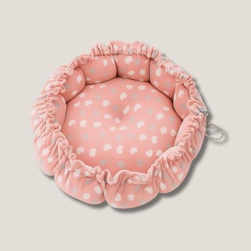 Couffin pour chat en polaire rose, vide, décoré de petits pois blancs et gris, présenté en vue de dessus sur fond neutre avec bord froncé.