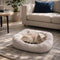Chat crème endormi dans un coussin apaisant moelleux beige clair, posé sur un tapis dans un salon cosy et lumineux.