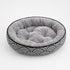 Coussin pour chaton rond en peluche grise avec rebords rembourrés et motif graphique noir et blanc, idéal pour un repos confortable.