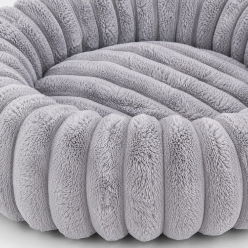 Gros plan d’un coussin rond pour chat gris en peluche ultra douce, mettant en valeur les reliefs rembourrés et la texture moelleuse du couchage.