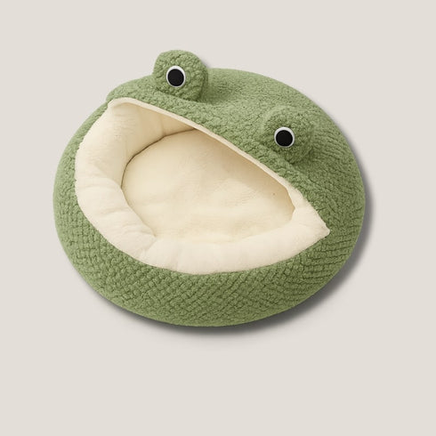 Coussin chat cocooning en polaire verte, design grenouille avec large ouverture doublée beige, présenté sur fond neutre en vue légèrement plongeante.