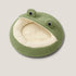 Coussin chat cocooning en polaire verte, design grenouille avec large ouverture doublée beige, présenté sur fond neutre en vue légèrement plongeante.