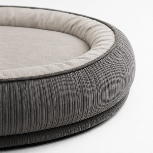 Gros plan sur le rebord en velours côtelé gris d’un grand lit pour chat avec coussin intérieur rembourré et finition douce.