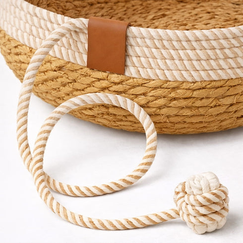 Gros plan sur la corde de jeu intégrée d’un panier en rotin pour chat en imitation rotin bicolore avec finition tressée et balle en corde sur fond clair.