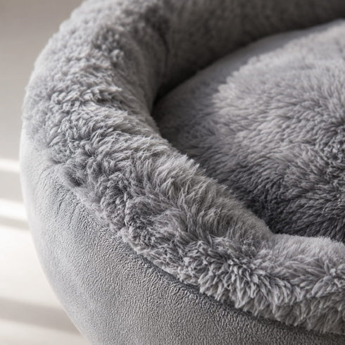 Gros plan sur la texture douce d’un panier rond pour chat gris en peluche épaisse avec finition moelleuse et confortable.