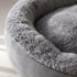 Gros plan sur la texture douce d’un panier rond pour chat gris en peluche épaisse avec finition moelleuse et confortable.