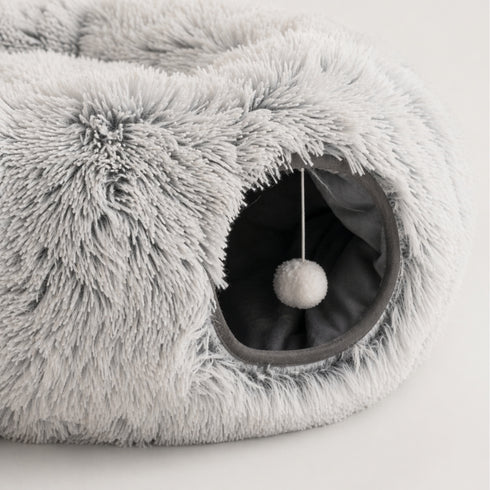 Gros plan sur le tunnel intégré d’une tanière pour chat grise en peluche avec pompon suspendu et intérieur doux visible