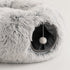 Gros plan sur le tunnel intégré d’une tanière pour chat grise en peluche avec pompon suspendu et intérieur doux visible