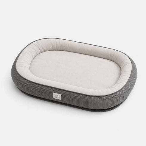 Grand lit pour chat gris avec rebords rembourrés et coussin intérieur blanc, conçu pour offrir un couchage spacieux et confortable.