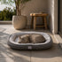 Grand lit pour chat gris avec coussin moelleux blanc, installé sur une terrasse lumineuse avec un chat allongé confortablement.