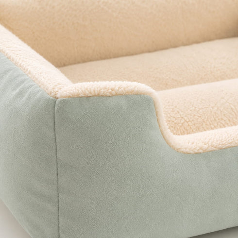 Gros plan sur un grand panier chat vert avec revetement doux et interieur moelleux creme mettant en avant la texture et le confort du couchage