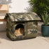 Grande maison pour chat extérieur camouflage avec toit rembourré, installée sur une terrasse avec un chat roux à l’intérieur