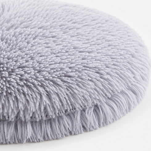 Gros plan sur un tapis apaisant pour chat en peluche grise ultra douce avec texture longue et moelleuse sur fond clair