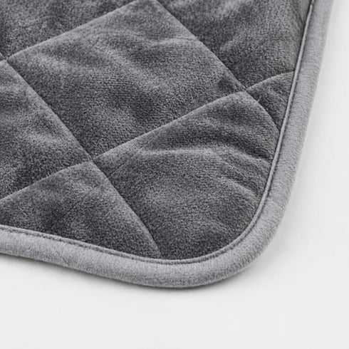Gros plan sur un tapis auto chauffant pour chat gris avec texture velours douce, coutures matelassées et finitions confortables