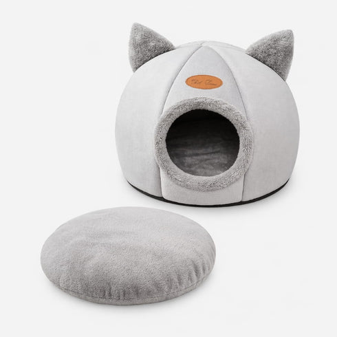 Grotte pour chat grise avec oreilles décoratives et coussin amovible assorti, présentée sur fond clair en photo produit