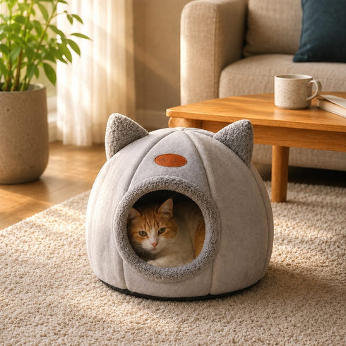 Chat installé dans une grotte pour chat grise en peluche dans un salon, profitant d'un cocon douillet et rassurant pour se reposer en toute tranquillité.