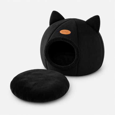 Grotte pour chat noire avec oreilles décoratives et coussin moelleux amovible, présentée sur fond clair en studio produit