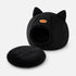 Grotte pour chat noire avec oreilles décoratives et coussin moelleux amovible, présentée sur fond clair en studio produit