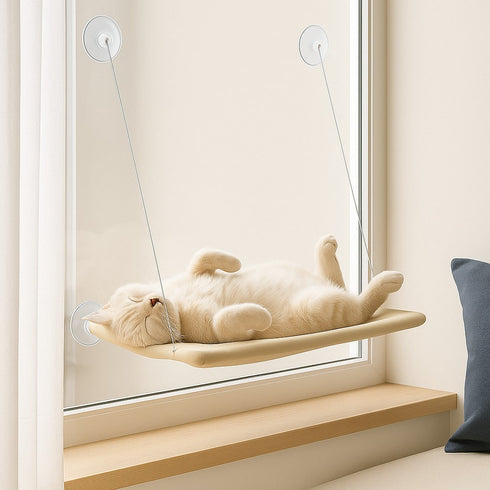 Hamac de fenêtre pour chat en tissu beige, fixé par ventouses sur une vitre, avec un chat allongé sur le dos profitant d’un espace de repos en hauteur.