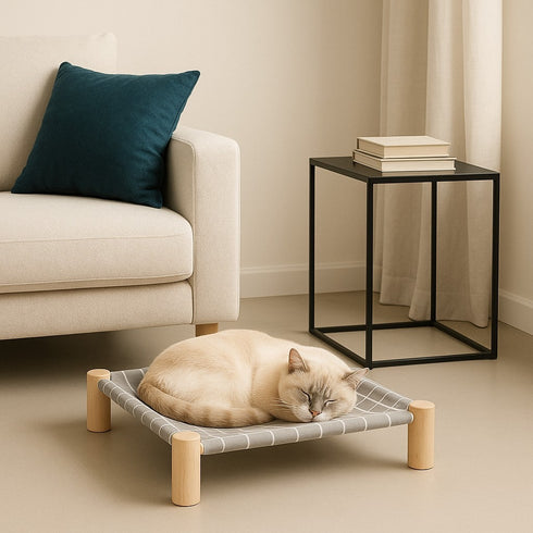 Hamac pour chat sur pied en bois clair avec toile grise, placé dans un salon moderne et épuré, accueillant un chat endormi et détendu.