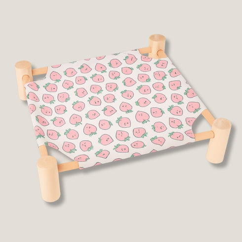 Hamac pour chat sur pied en bois clair avec toile rose à motif fruits, présenté seul en photo studio sur fond neutre.