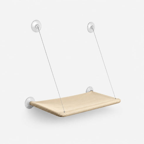 Hamac de fenêtre pour chat beige suspendu avec ventouses transparentes et câbles métalliques, présenté sur fond neutre en studio.