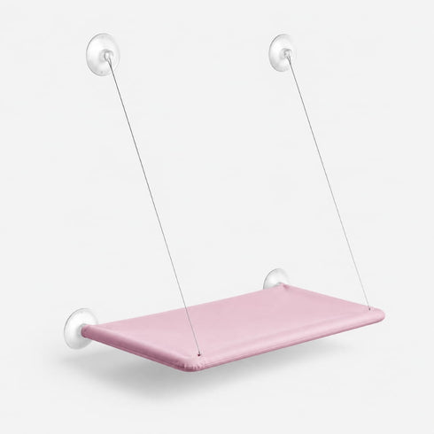 Hamac de fenêtre pour chat rose suspendu avec ventouses transparentes et câbles métalliques, présenté sur fond neutre en studio.