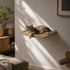 Chat tigré allongé sur un hamac mural pour chat en bois clair et tissu beige, parfait pour un coin repos confortable et design.