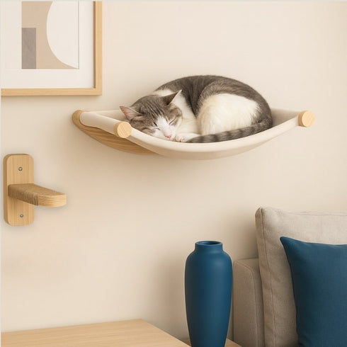 Hamac mural pour chat en bois avec toile beige, fixé au mur, avec un chat endormi dans un intérieur chaleureux.