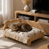 Lit en bois pour chat avec coussin à motifs ours et chat tigré allongé dans un salon chaleureux au style naturel et cosy