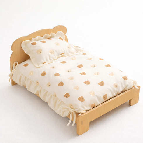 Lit en bois pour chat avec couette crème à motifs ours, oreiller assorti et finitions à volants sur fond studio épuré