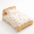 Lit en bois pour chat avec couette crème à motifs ours, oreiller assorti et finitions à volants sur fond studio épuré