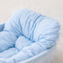 Gros plan sur le rembourrage moelleux et le tissu à carreaux bleus du lit pour chaton avec finition délicate à volants.