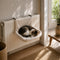 Chat endormi dans un lit radiateur pour chat en peluche beige, suspendu au chauffage pour offrir un couchage chaud et douillet.