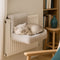 Lit radiateur pour chat en peluche beige, fixé au radiateur, avec un chat endormi confortablement.