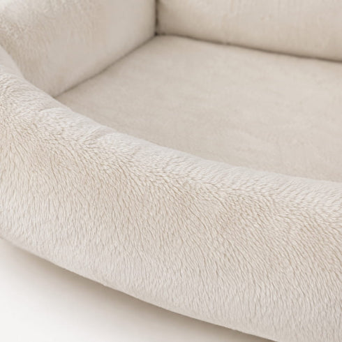 Gros plan sur le revêtement en peluche crème ultra douce d’un lit radiateur pour chat avec rebords confortables et moelleux.