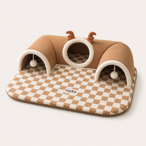 Lit tunnel pour chat marron avec tapis à carreaux, cachettes intégrées et jouets suspendus sur fond studio épuré.