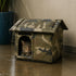 Grande maison pour chat extérieur camouflage sous la pluie avec toit imperméable et chat tigré abrité sur une terrasse humide
