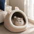 Maison douillette rose pour chat avec oreilles de lapin et intérieur moelleux, installée près d’une fenêtre lumineuse avec un chat allongé à l’intérieur