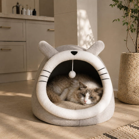 Maison douillette grise pour chat avec design inspiré d’un animal et intérieur moelleux, installée dans une pièce lumineuse avec un chat allongé à l’intérieur