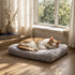 Chat allongé sur un matelas pour chat gris en peluche douce, couchage moelleux et confortable près d’une fenêtre lumineuse.