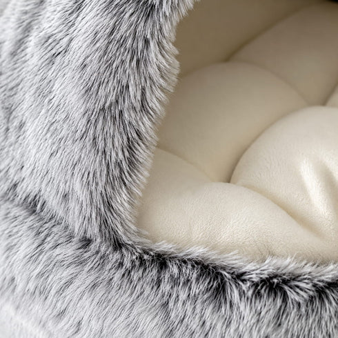 Gros plan sur la texture en peluche grise ultra douce et le coussin moelleux d’un nid pour chat, conçu pour un confort chaleureux et apaisant.