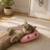 Chat allongé dormant avec la tête posée sur un petit oreiller rose à motifs fraise dans un intérieur lumineux.